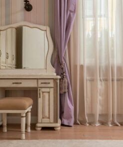 A stylish vanity desk with mirror in a sunlit bedroom featuring soft, elegant decor.